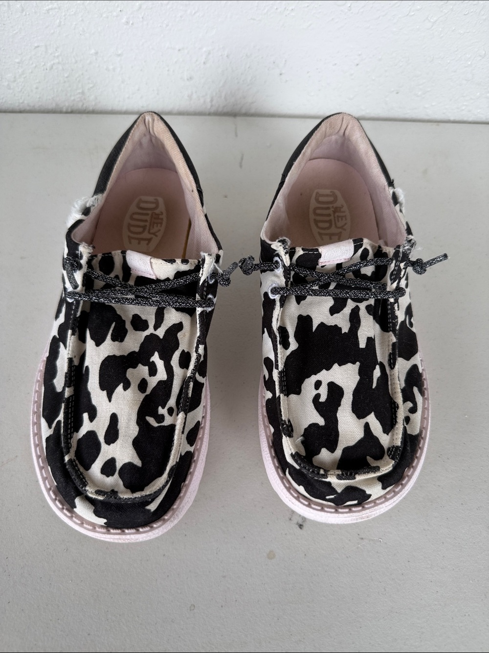 Hey Dude Kids Cow Print Slip-On Shoes in Black & White with Pink Trim